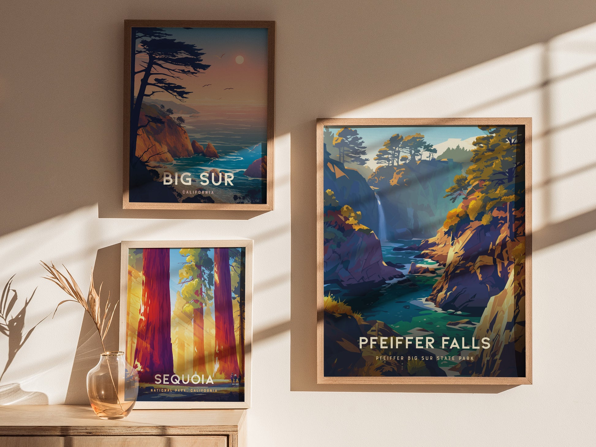 Three framed posters on a sunlit wall depict scenic California landscapes: Big Sur, a coastal view; Pfeiffer Falls, a waterfall; and Sequoia, featuring towering redwoods.