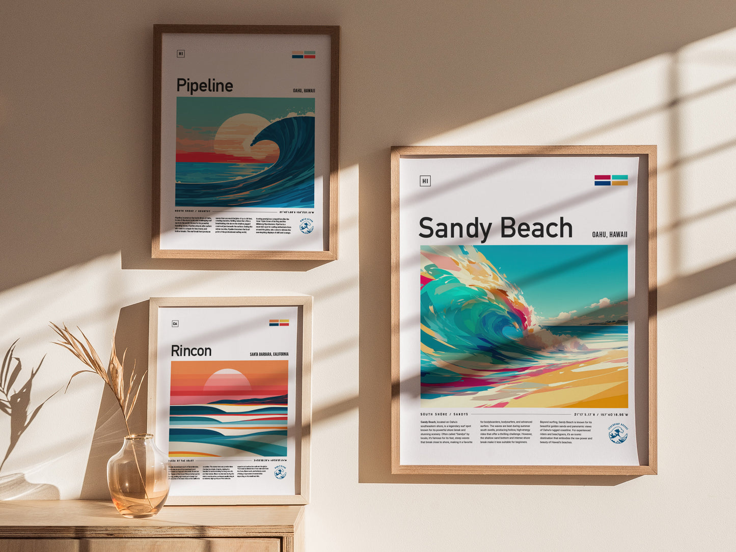 Three framed posters hang on a sunlit wall, featuring vibrant illustrations of waves labeled Pipeline, Sandy Beach, and Rincon. A small vase with dried grasses sits below.