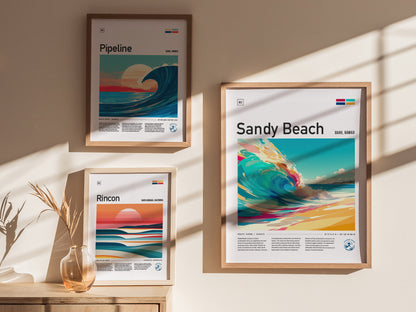 Three framed posters hang on a sunlit wall, featuring vibrant illustrations of waves labeled Pipeline, Sandy Beach, and Rincon. A small vase with dried grasses sits below.
