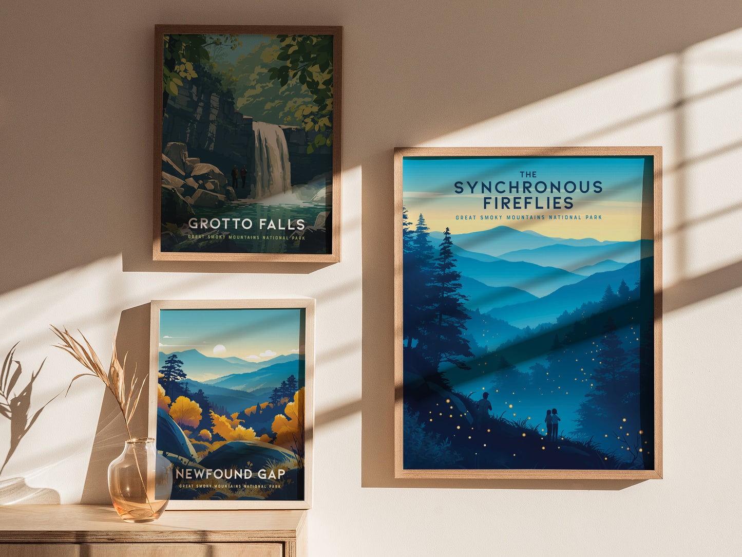Three framed posters are displayed on a wall, showcasing nature scenes from Great Smoky Mountains National Park: Grotto Falls with a waterfall, Newfound Gap with mountains at sunset, and Synchronous Fireflies with a night sky.