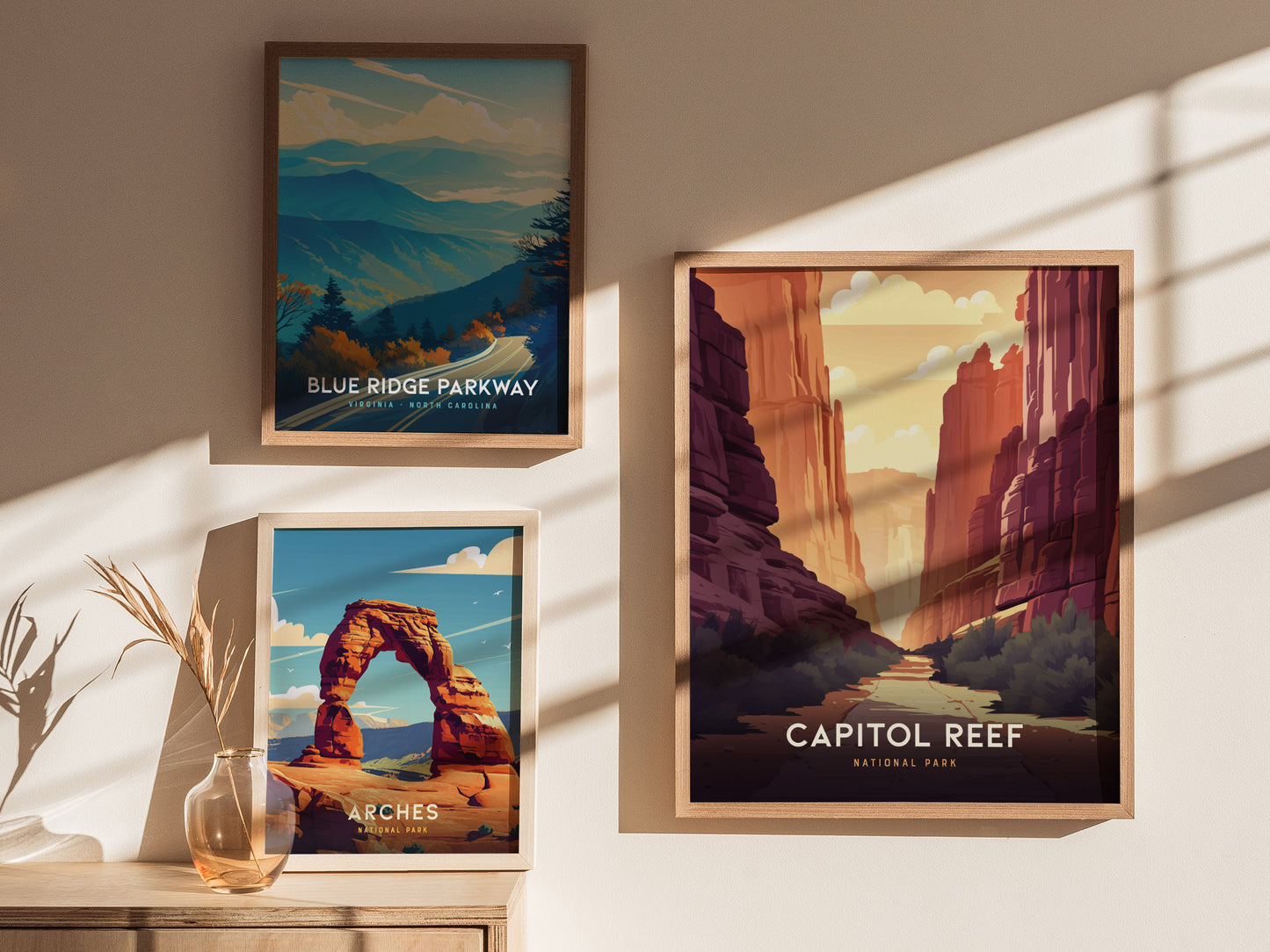 Three framed posters on a wall depict scenic landscapes: Blue Ridge Parkway, Arches National Park, and Capitol Reef National Park, with natural lighting casting shadows.