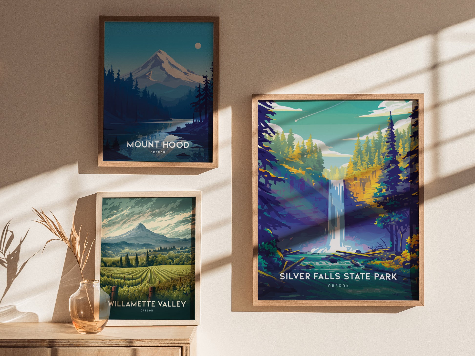 Three framed posters on a sunlit wall feature Mount Hood, Willamette Valley, and Silver Falls State Park, each depicting scenic Oregon landscapes with mountains and waterfalls.