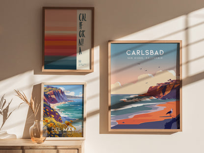 Three framed posters are displayed on a sunlit wall, featuring vibrant illustrations of California, Carlsbad, and Del Mar coastal scenes, complemented by a vase with dried plants.