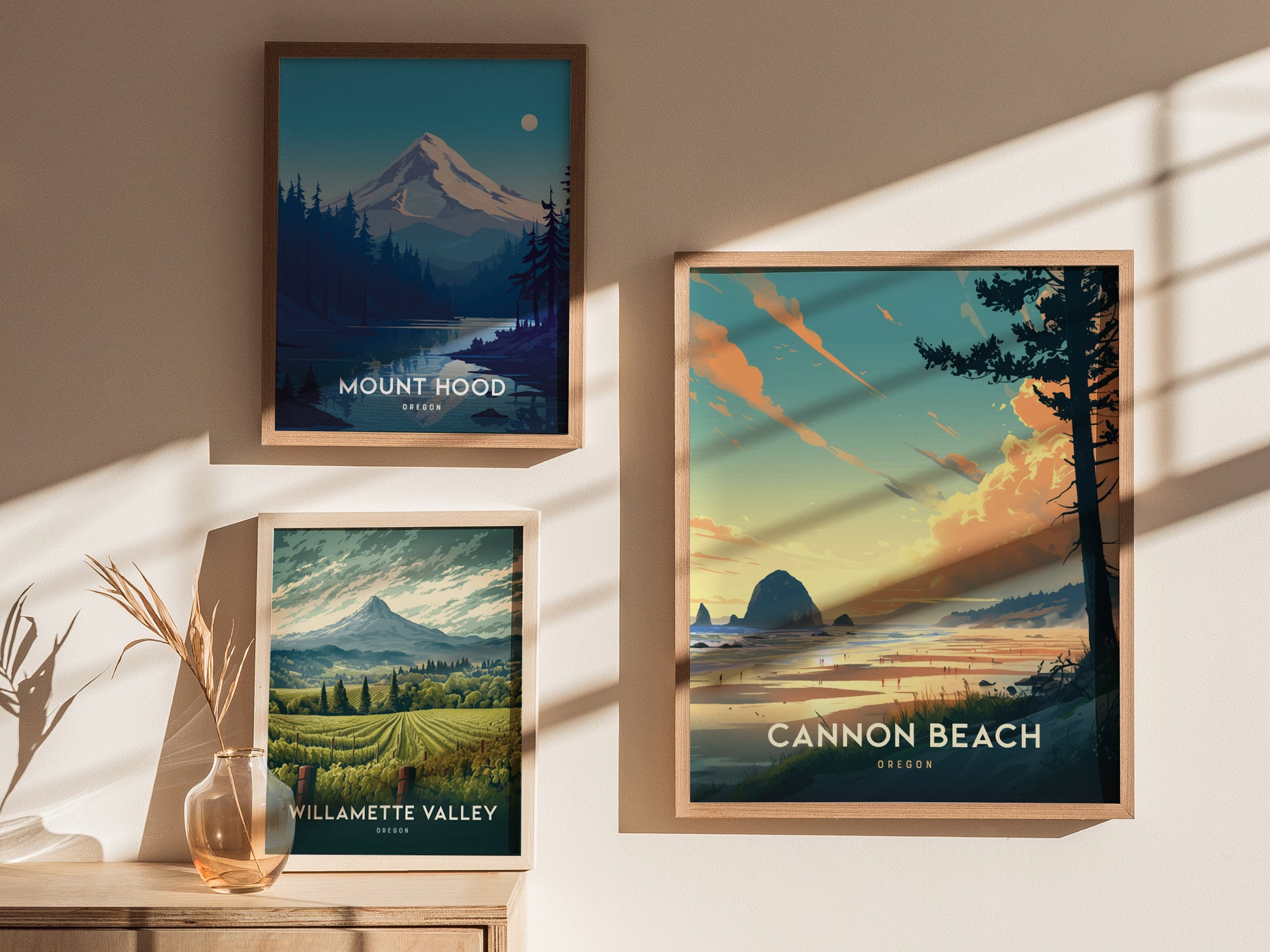 Three framed posters on a sunlit wall depict Oregon landscapes: Cannon Beach with Haystack Rock, Mount Hood under a moonlit sky, and lush Willamette Valley with rolling vineyards.