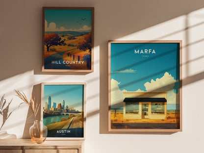 Three framed posters are displayed on a sunlit wall, featuring scenes from Hill Country, Austin, and Marfa, Texas, with a vase of dried plants on a wooden surface.