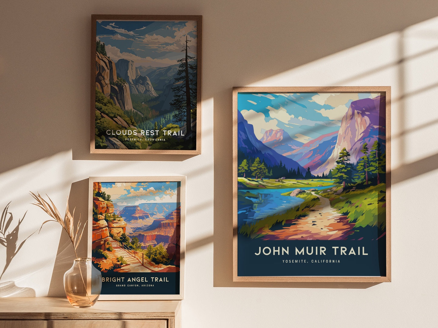 Three framed posters are displayed on a sunlit wall, featuring scenic trails: Clouds Rest Trail, Bright Angel Trail, and John Muir Trail, each with vibrant landscapes.
