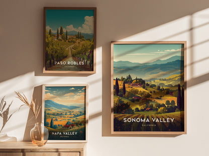 Framed posters of Paso Robles, Napa Valley, and Sonoma Valley are displayed on a sunlit wall. A glass vase with dried grasses sits on a wooden surface below.