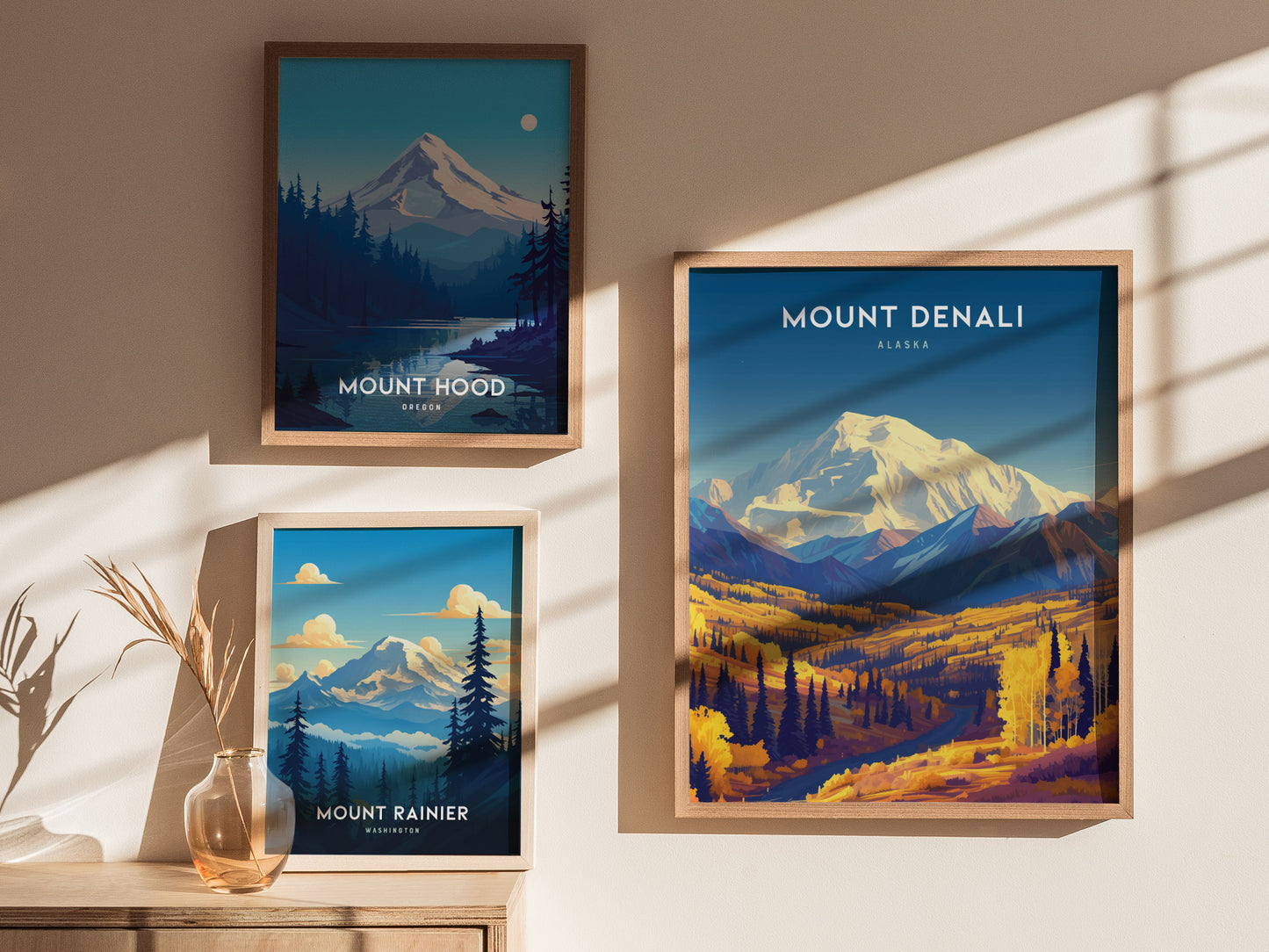 Three framed mountain posters are displayed on a wall. They depict Mount Denali, Mount Hood, and Mount Rainier, each with vibrant colors and scenic landscapes.