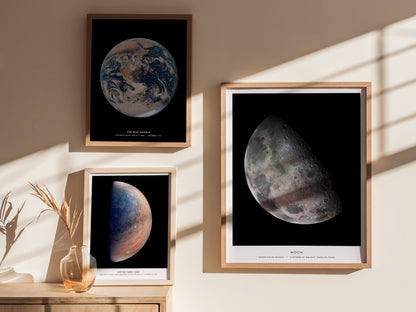 Framed posters of Earth and the Moon on a wall with sunlight casting shadows.