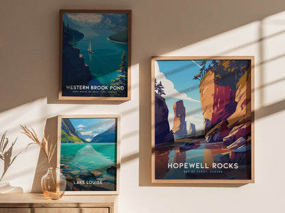 Three framed posters are displayed on a sunlit wall, showcasing Western Brook Pond, Lake Louise, and Hopewell Rocks, each featuring vibrant natural landscapes. A vase with dried plants sits below.