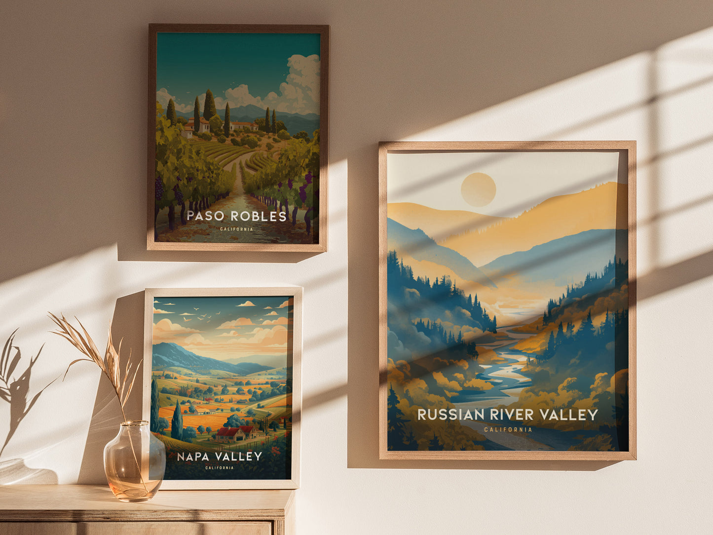 Three framed posters of Paso Robles, Napa Valley, and Russian River Valley are displayed on a sunlit wall, showcasing vibrant landscapes of Californias wine regions.