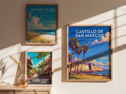 Three framed posters are displayed on a wall, featuring Castillo de San Marcos, Anastasia Island, and St. George Street in St. Augustine, Florida, with sunlight casting shadows.