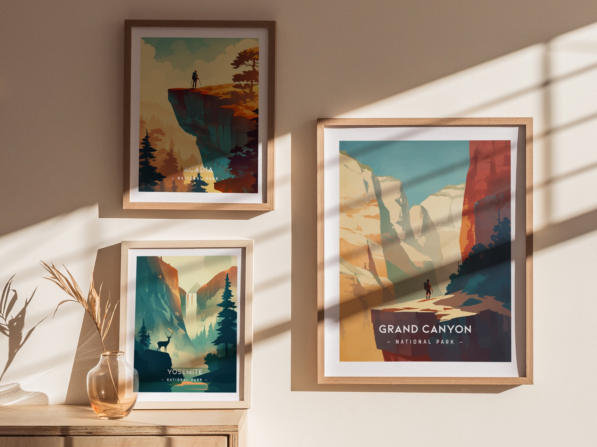 Three framed minimalist posters of national parks are displayed on a sunlit wall. The posters feature Acadia, Yosemite, and Grand Canyon, each with stylized natural landscapes.