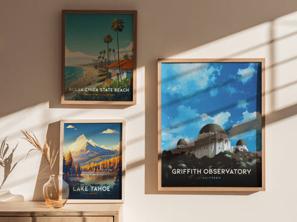 Three framed posters are displayed on a wall, featuring Bolsa Chica State Beach, Lake Tahoe, and Griffith Observatory, with natural light casting shadows across them.