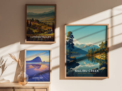 Three framed posters are displayed on a sunlit wall, featuring scenic landscapes of Sonoma Valley, Morro Bay, and Malibu Creek State Park with vibrant colors and natural beauty.