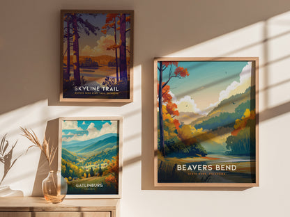 Three framed posters are displayed on a sunlit wall, featuring scenic illustrations of Skyline Trail, Beavers Bend State Park, and Gatlinburg with vibrant landscapes and colorful foliage.