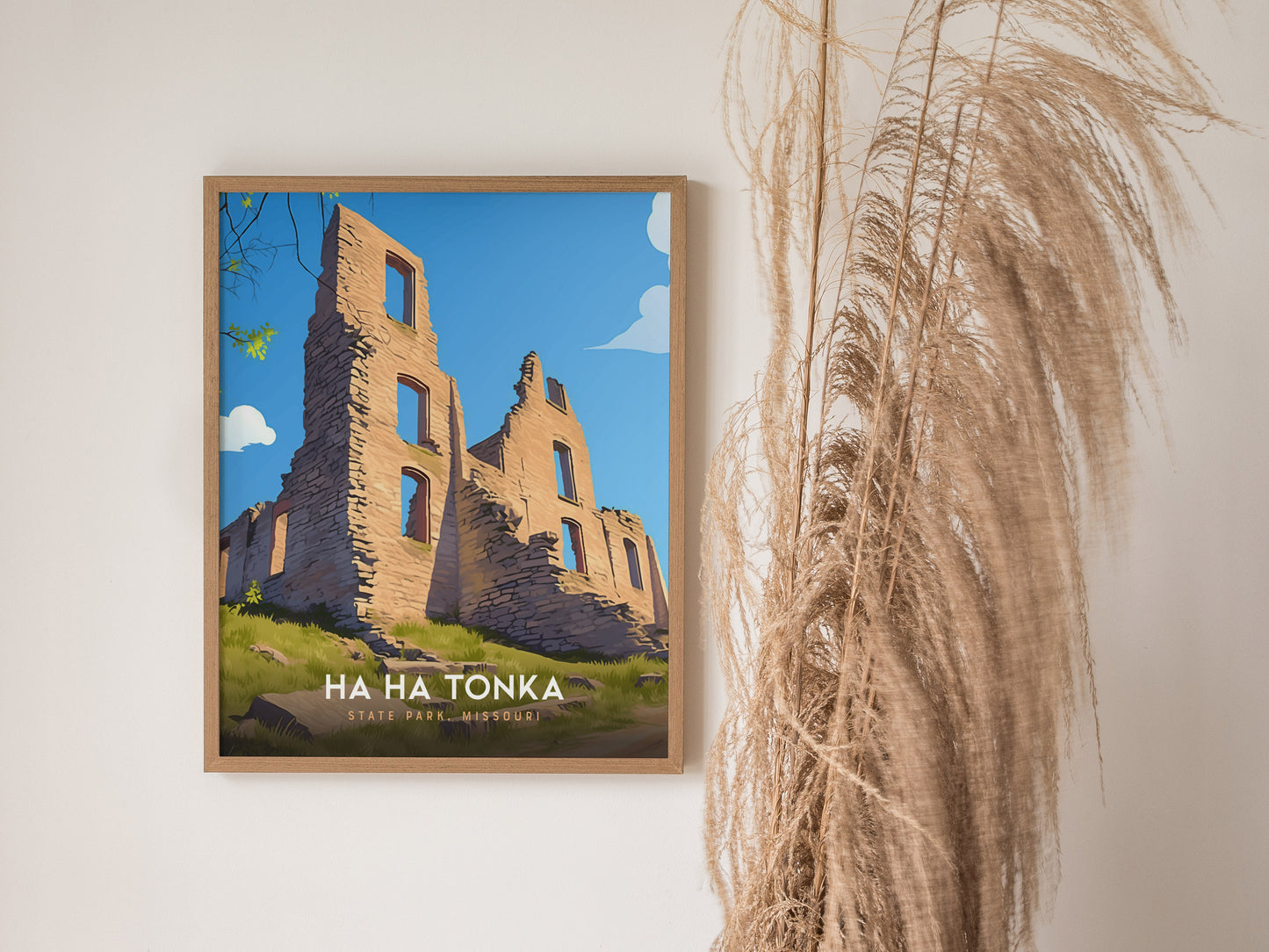 Framed artwork of Ha Ha Tonka State Park in Missouri, featuring stone ruins under a clear blue sky. Decorative dried grasses are visible beside the framed print.