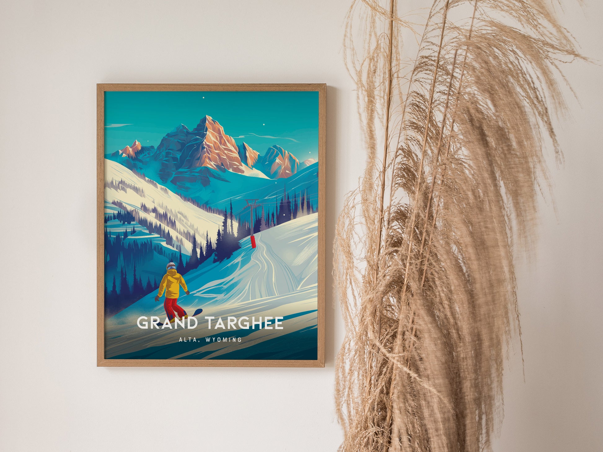 A framed poster of Grand Targhee Resort features a snowboarder on snowy slopes with majestic mountains in the background. Dried pampas grass decorates the adjacent wall space.