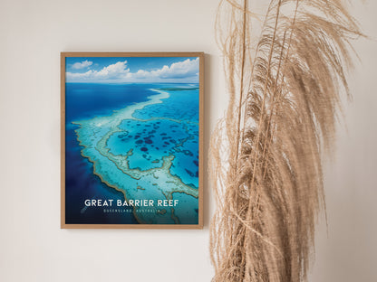 A framed poster of the Great Barrier Reef hangs on a white wall, featuring vivid turquoise waters and coral formations. Pampas grass decorates the right side, adding texture.