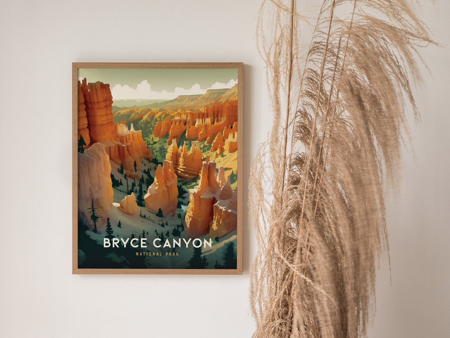 Framed artwork of Bryce Canyon National Park featuring vibrant orange and red hoodoos, displayed on a light-colored wall next to tall, dried pampas grass.