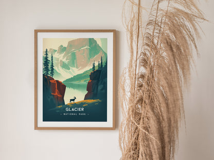 A framed minimalist poster of Glacier National Park features a lone bighorn sheep, a glassy lake, and towering peaks. Its displayed against a light wall with dried pampas grass.