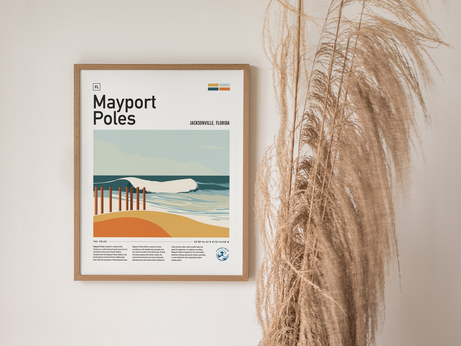 A framed poster titled Mayport Poles depicts a stylized beach scene with waves and sand dunes, hung on a wall next to tall, dried grasses.