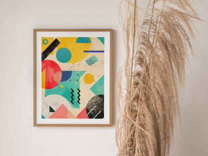 A framed abstract poster featuring bold geometric shapes in vibrant colors hangs on a wall beside dried pampas grass. The artwork showcases 90s-inspired retrowave design elements.