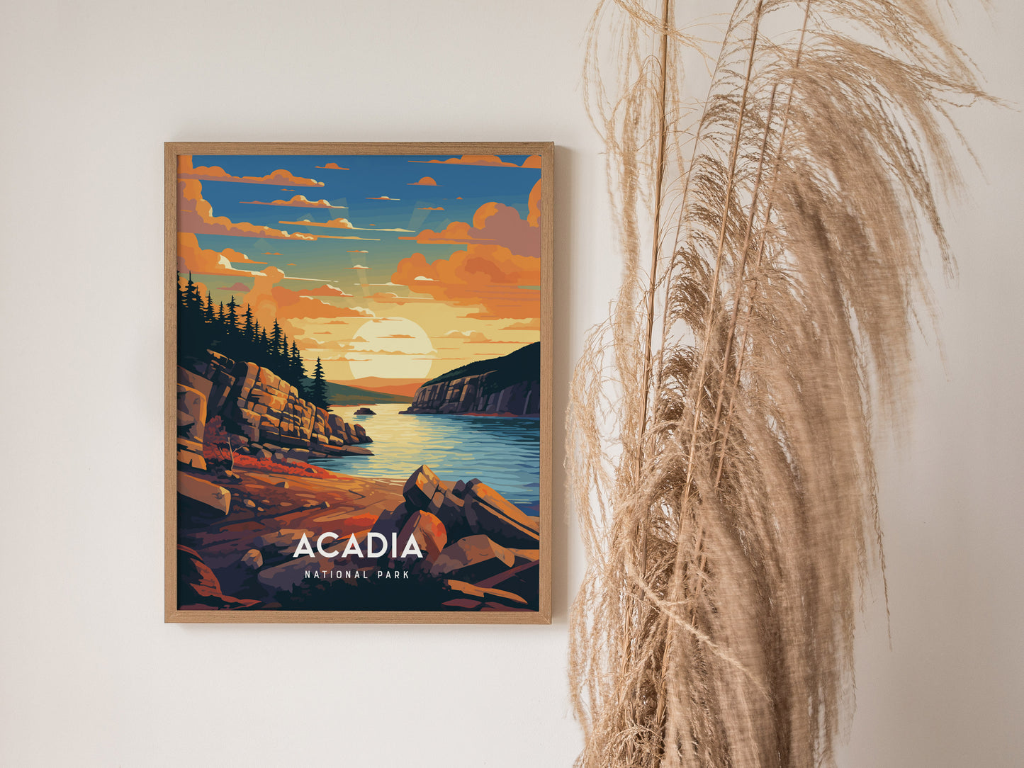 A framed poster of Acadia National Park depicts a vibrant sunset over rocky cliffs and a serene coastal scene, with tall grasses in the foreground.