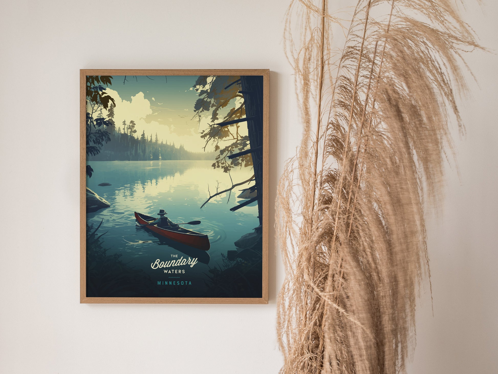 A framed poster depicting a serene canoeing scene in Boundary Waters, Minnesota, hangs on a wall next to dried pampas grass. The artwork features a tranquil lake and forest.