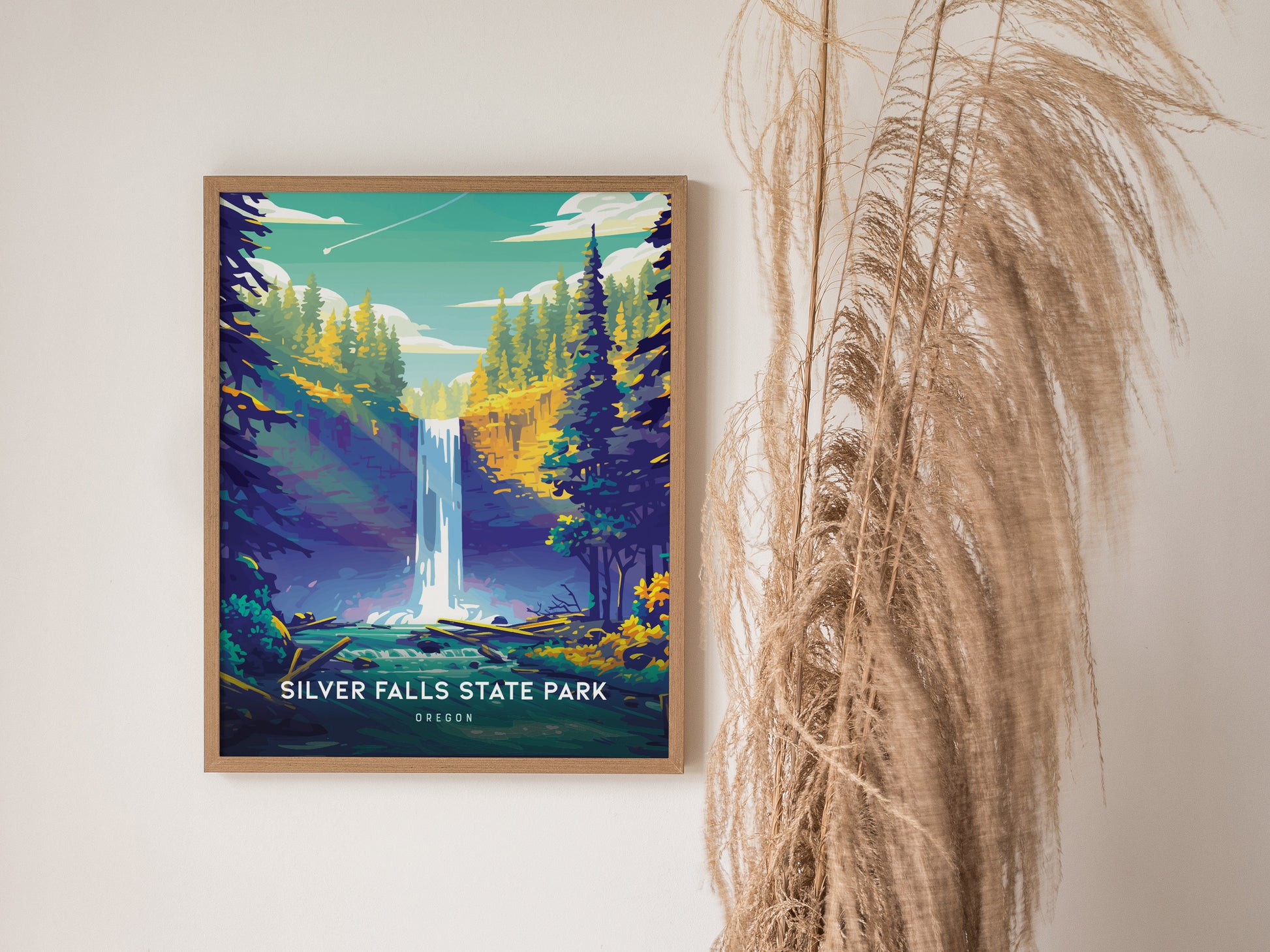 Framed poster of Silver Falls State Park featuring a vibrant waterfall surrounded by lush green and yellow trees, with pampas grass decoratively placed beside it.
