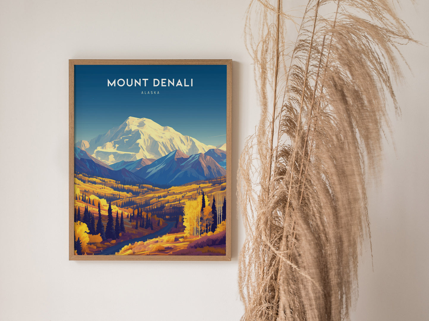 A framed Mount Denali poster features a colorful landscape of mountains and trees, with pampas grass decor on the right. The poster has a vibrant, artistic design.