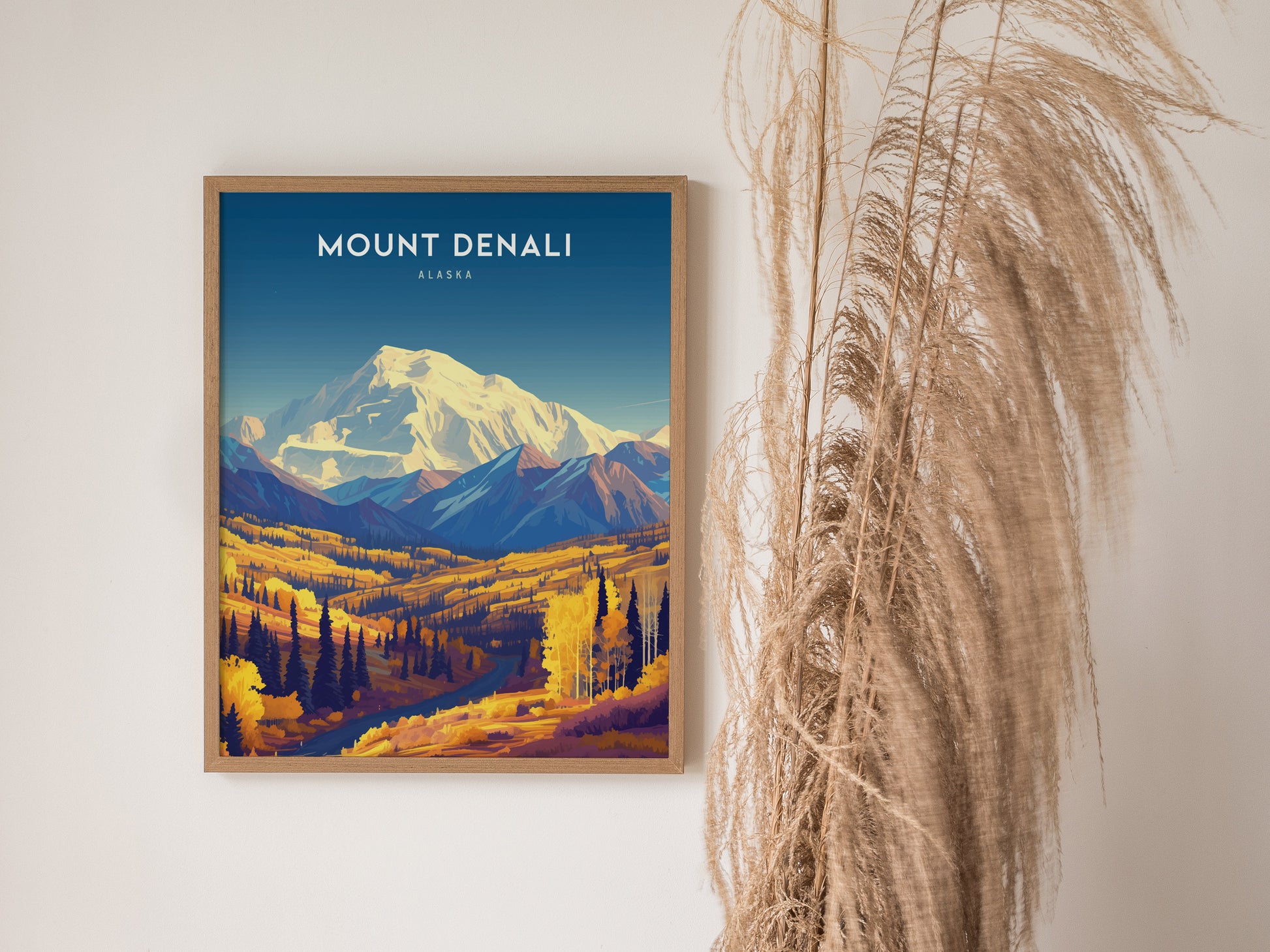 A framed Mount Denali poster features a colorful landscape of mountains and trees, with pampas grass decor on the right. The poster has a vibrant, artistic design.
