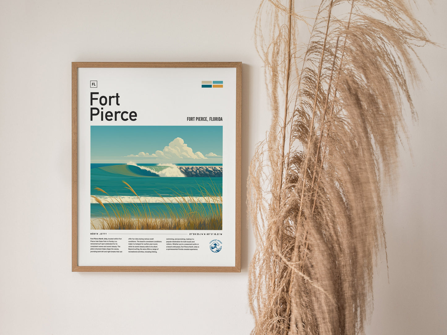 A framed poster of Fort Pierce, Florida, features an ocean scene with waves and a jetty, alongside beach grass. Dried pampas grass decorates the right side of the wall.