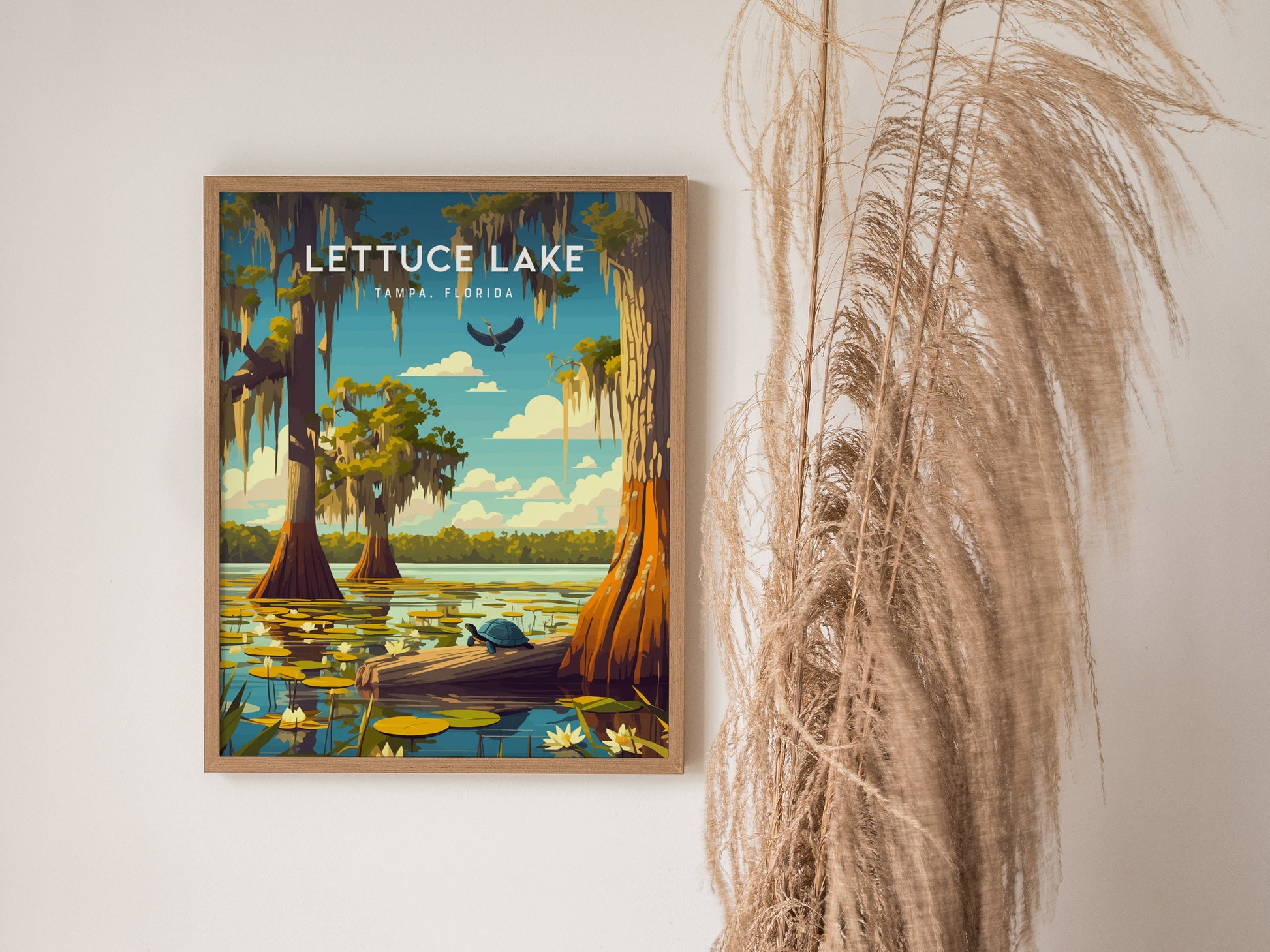 Framed artwork of Lettuce Lake Park features cypress trees, a turtle on a log, and lily pads under a blue sky. Tall dried grasses are visible beside the poster.