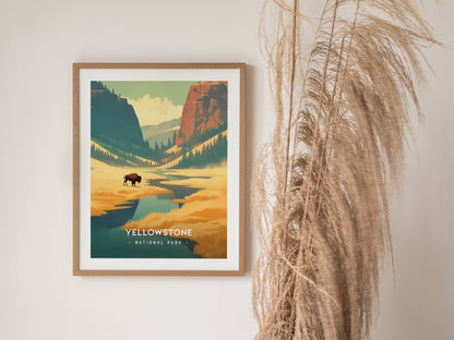 Framed Yellowstone National Park poster featuring a buffalo in a scenic landscape with mountains and trees, displayed on a wall beside tall dried grasses.