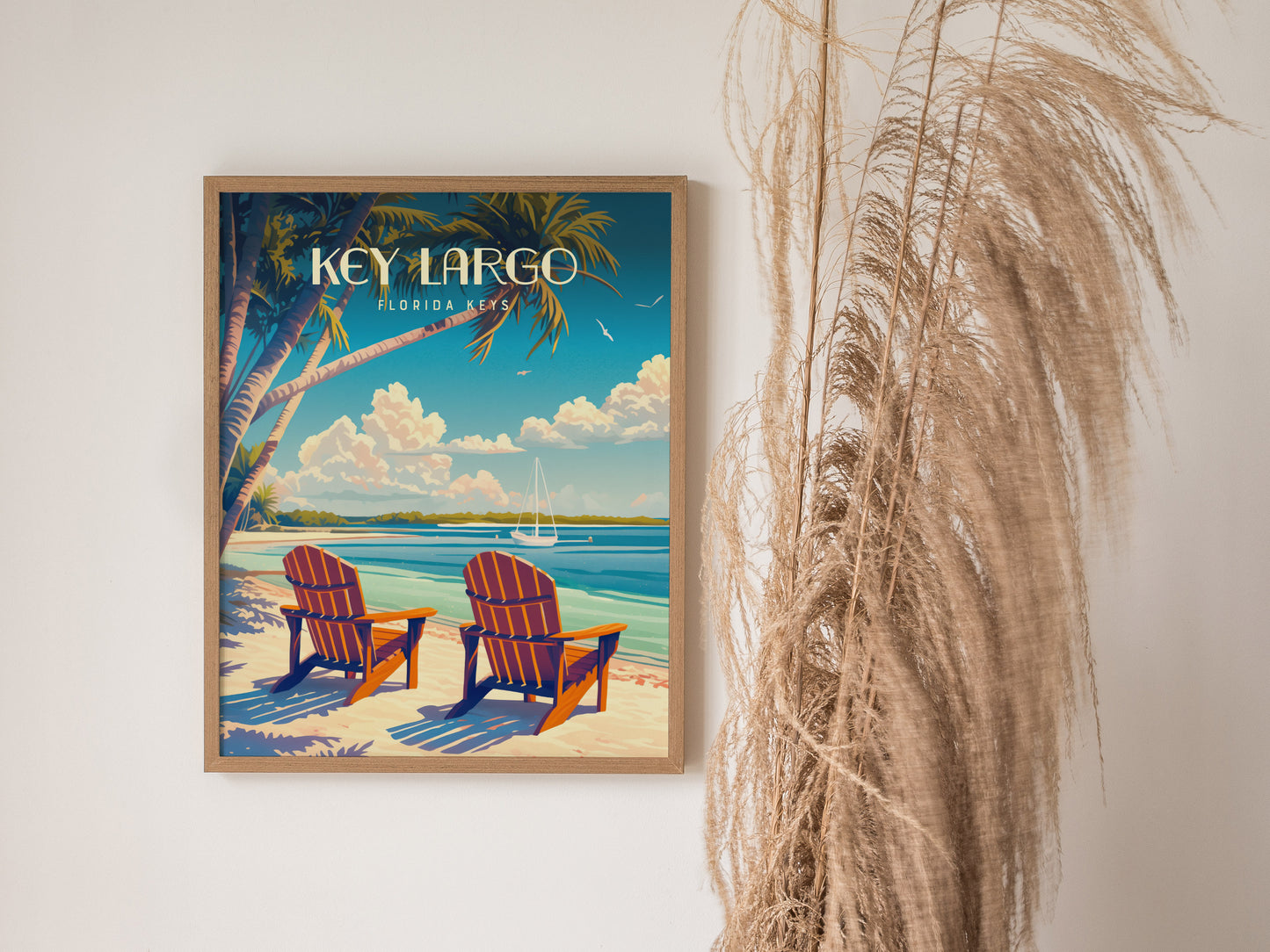 A framed poster of Key Largo, Florida Keys, shows two beach chairs under palm trees facing turquoise waters. Nearby, tall, dried grasses complement the serene coastal artwork.