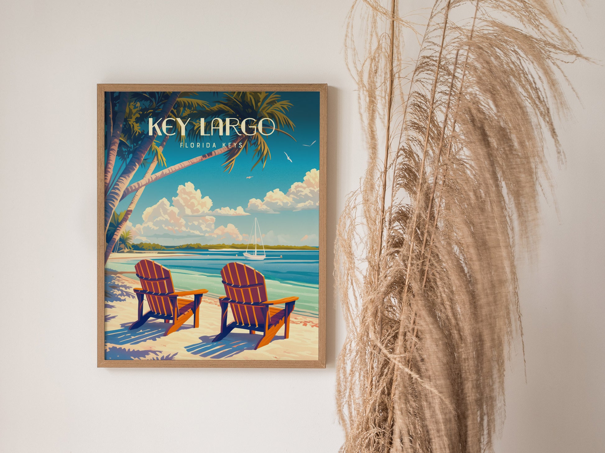A framed poster of Key Largo, Florida Keys, shows two beach chairs under palm trees facing turquoise waters. Nearby, tall, dried grasses complement the serene coastal artwork.
