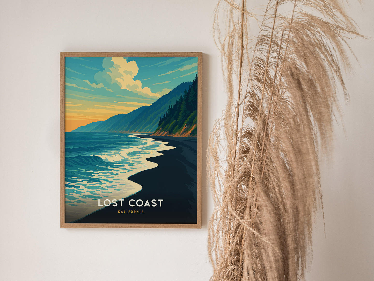Framed Lost Coast California poster showcases a vibrant ocean scene with crashing waves, forested hills, and a warm sunset sky.