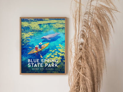 A framed poster of Blue Spring State Park shows two kayakers near a manatee in vibrant blue and green waters, with decorative grass beside it.