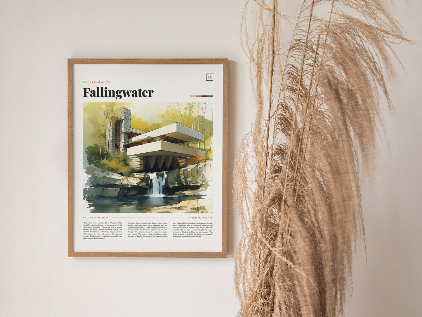 A framed Fallingwater poster featuring a watercolor illustration of the iconic architecture hangs on a wall next to tall, dried pampas grass.