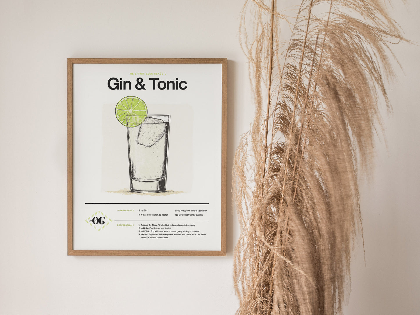 A framed poster titled Gin & Tonic displays a minimalist sketch of the cocktail with a lime garnish. Its mounted on a wall next to pampas grass decor.