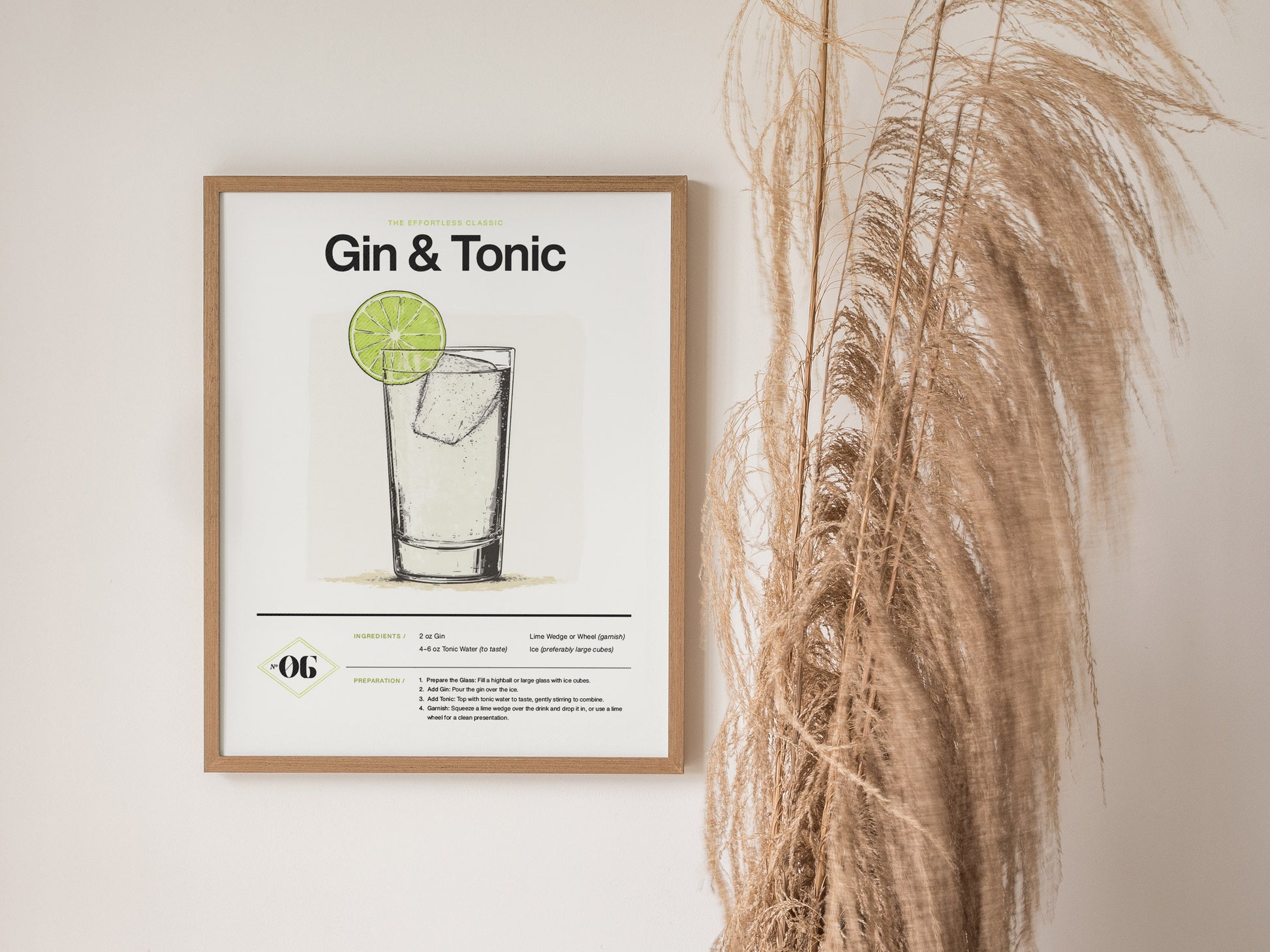 A framed poster titled Gin & Tonic displays a minimalist sketch of the cocktail with a lime garnish. Its mounted on a wall next to pampas grass decor.