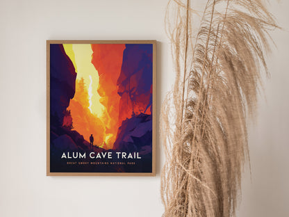 A framed poster titled Alum Cave Trail depicts a vibrant, colorful landscape with a lone hiker silhouetted against a dramatic canyon. Dried pampas grass decorates the scene.