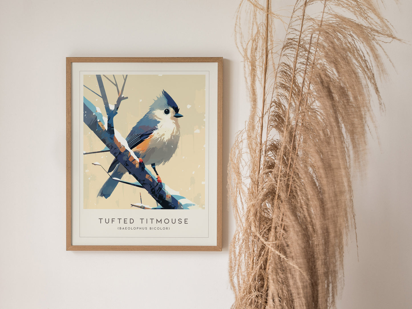 A framed poster of a Tufted Titmouse is displayed on a wall, showcasing the bird perched on a branch with its distinctive crest and colorful plumage. Beside it, tall dried grasses add a natural touch to the scene.