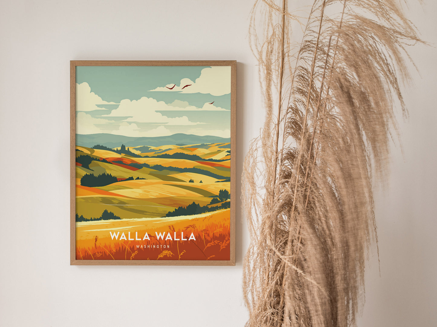 A framed poster of Walla Walla, Washington, displays vibrant rolling hills and fields under a partly cloudy sky, with decorative dried grasses beside it.