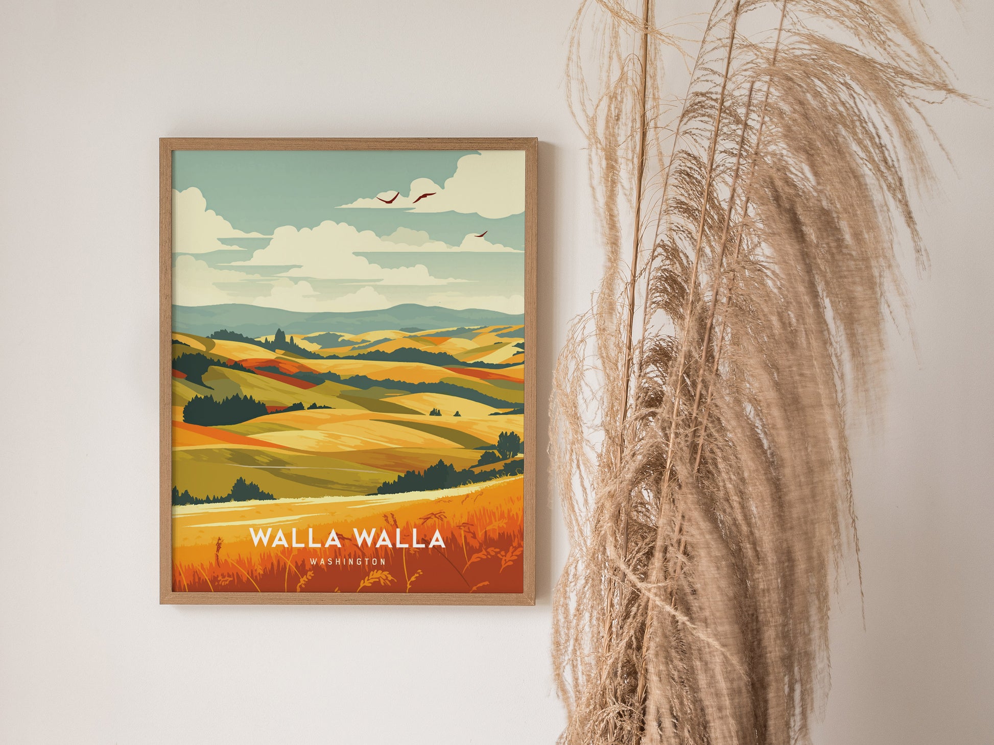 A framed poster of Walla Walla, Washington, displays vibrant rolling hills and fields under a partly cloudy sky, with decorative dried grasses beside it.