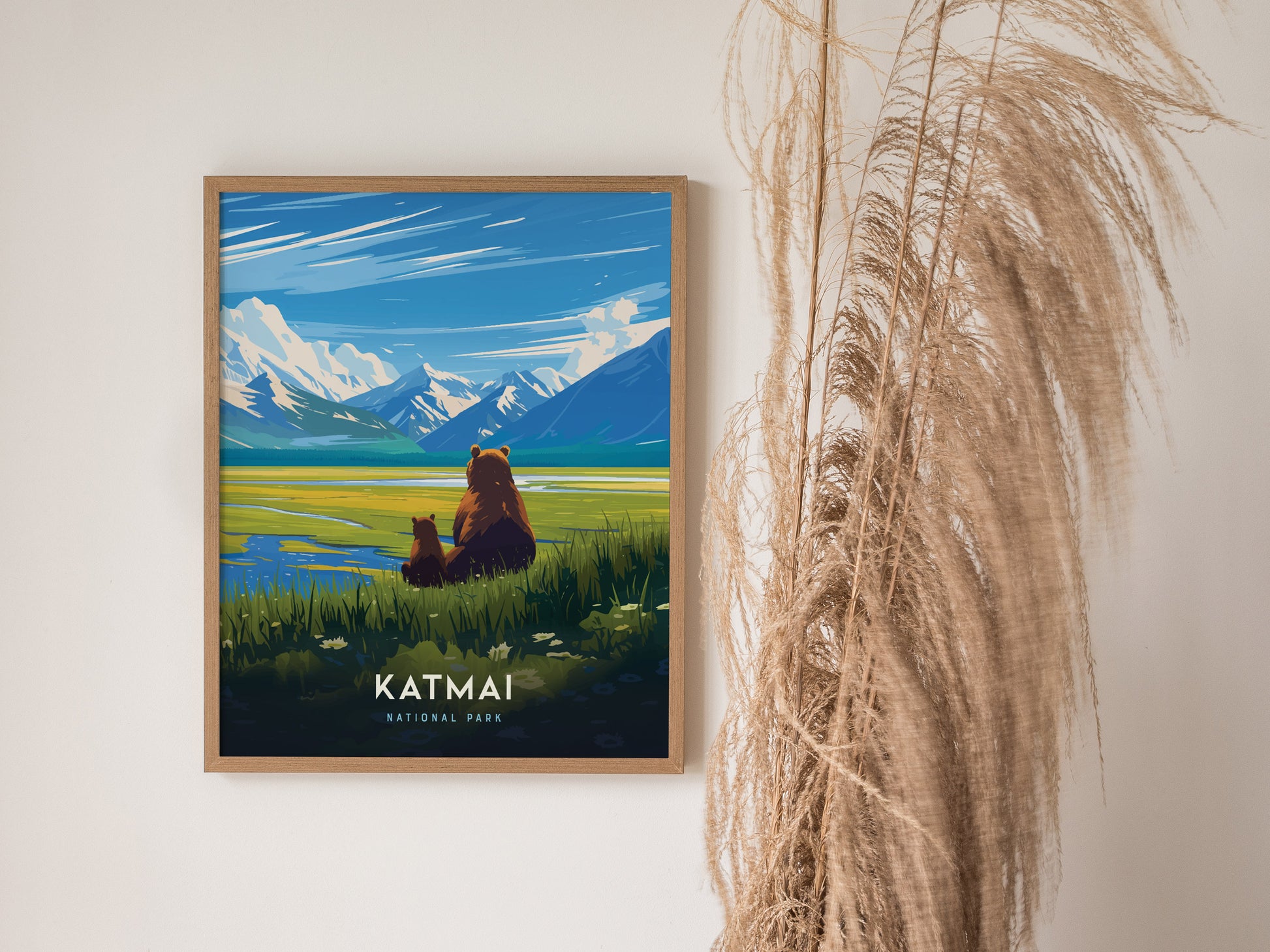 Framed Katmai National Park poster depicting a serene landscape with two brown bears overlooking a vibrant river and snow-capped mountains, next to decorative dried grasses.