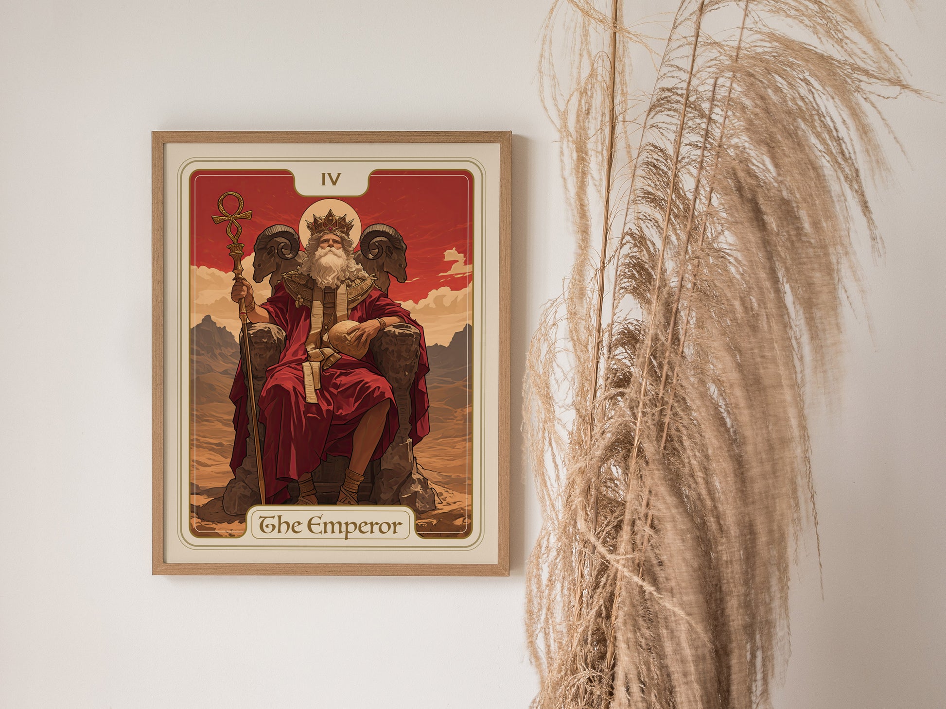 A framed Emperor Tarot card poster featuring an enthroned figure in red robes, holding an orb and scepter, is displayed next to tall, wispy pampas grass.
