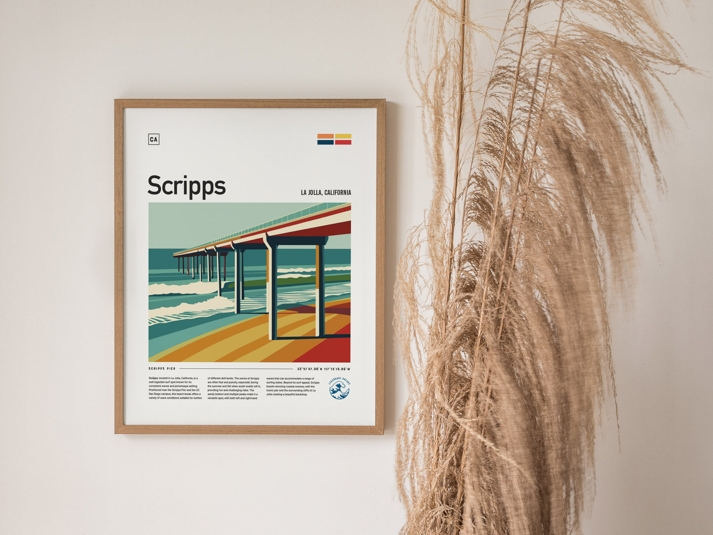 Framed poster of Scripps Pier in La Jolla, California, featuring bold lines and vibrant colors, hangs on a wall beside tall, dried ornamental grasses.