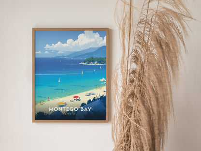A framed Montego Bay poster features a vibrant beach scene with turquoise water and sailboats, next to tall, dried pampas grass against a neutral wall.